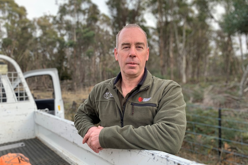 Man resting his hands on the back of a ute. 