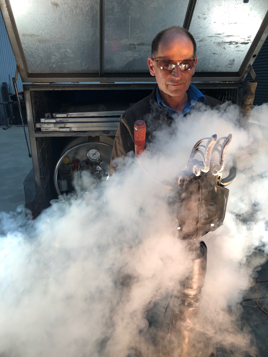 Dr John Steinfort wears goggles and operates his sheep freeze branding equipment.