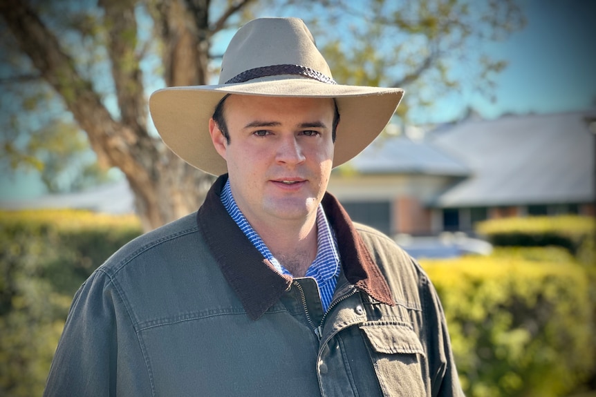 A man in a cowboy hat looks at the camera