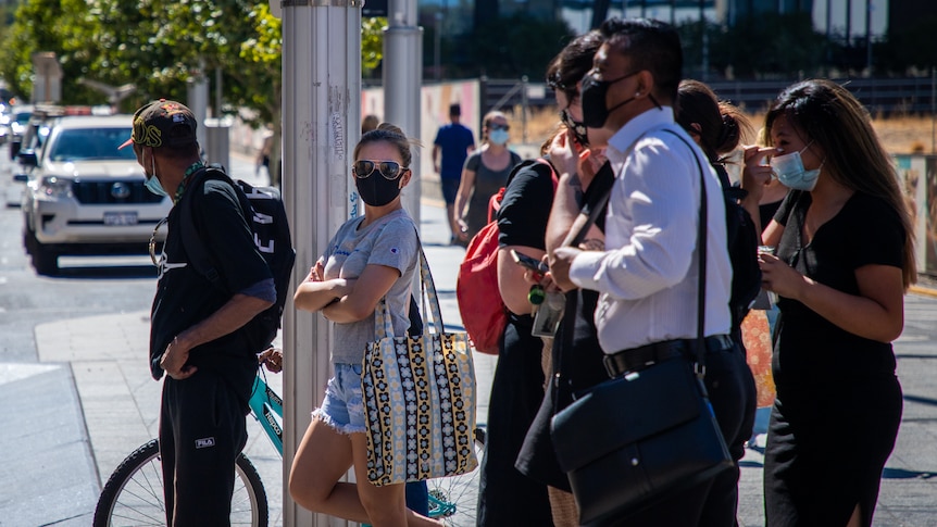 Pedestrians wearing face masks wait at a traffic crossing in Perth's CBD.