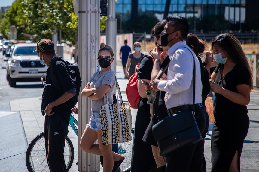 Pedestrians wearing face masks wait at a traffic crossing in Perth's CBD.