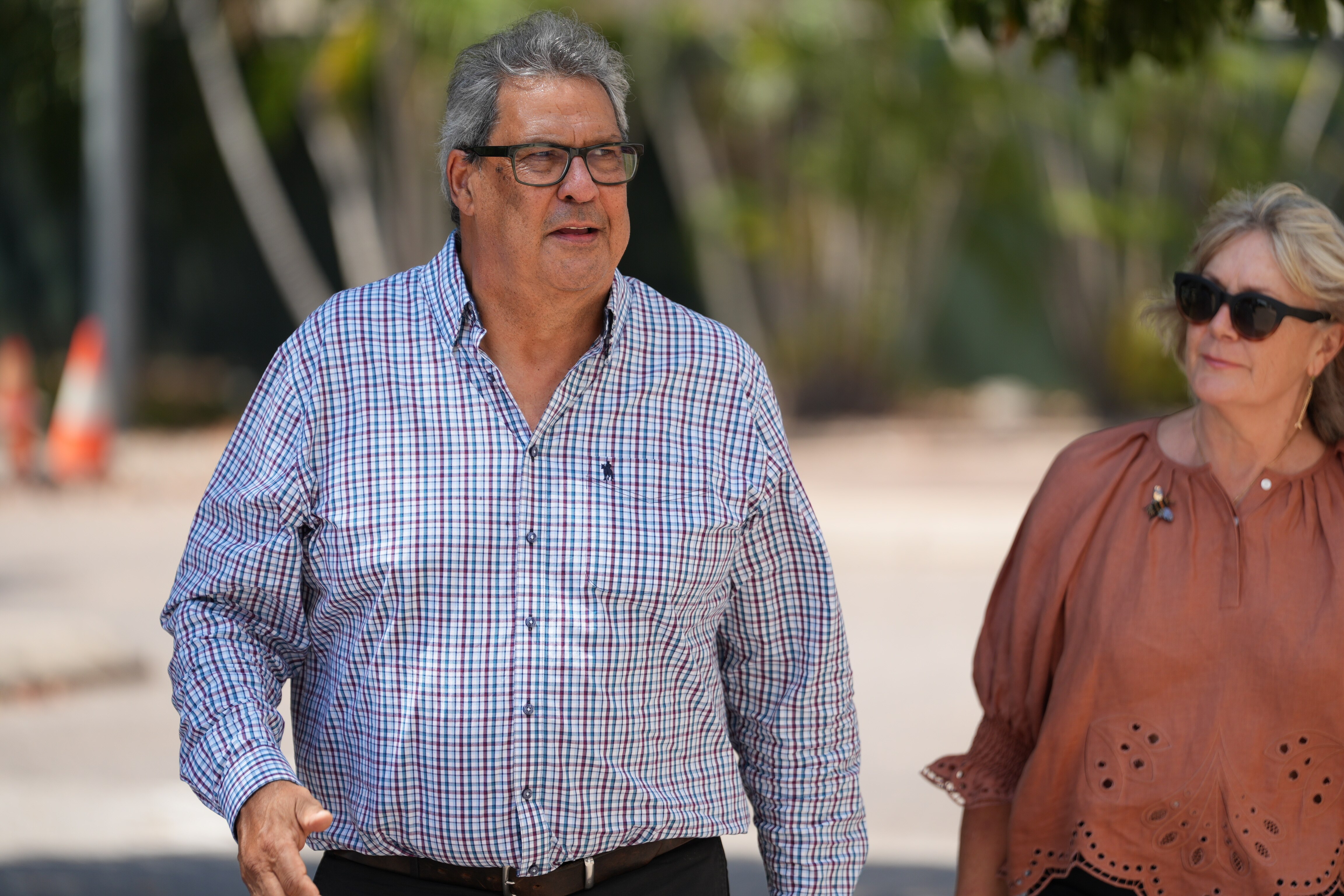 Um homem de óculos caminha com sua esposa.