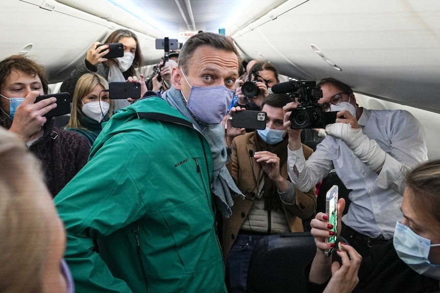 Alexei Navalny surrounded by reporters on a plane.