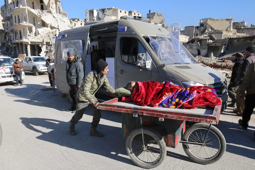 Man pushes a cart carrying injured woman in Aleppo