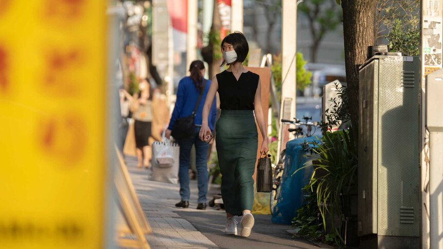 A woman in a face mask walks down a street