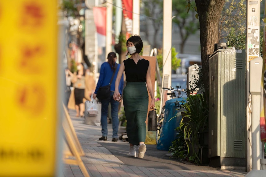 A woman in a face mask walks down a street