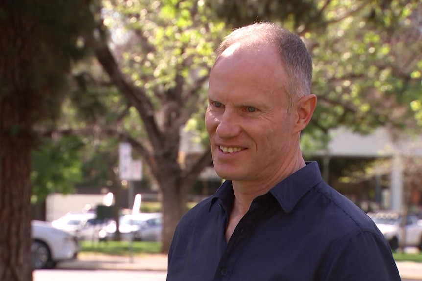 A man wearing a blue shirt smiling at the camera