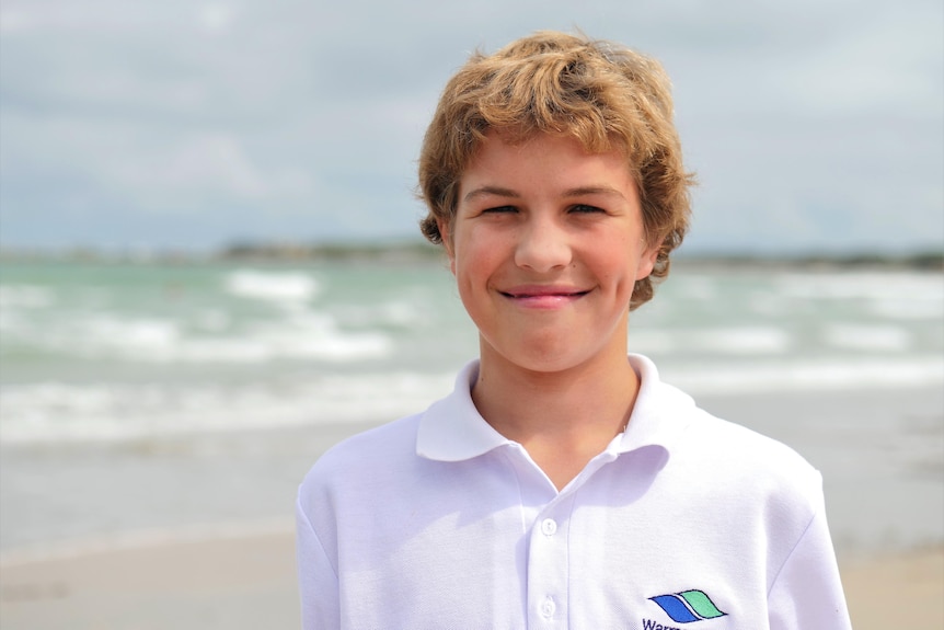 A very sweet young man fourteen years-old smiles with dimples wearing white Warrnambool college school t-shirt