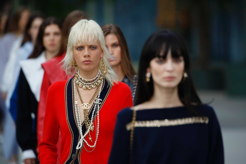 Models walk in a single file down the catwalk, wearing black, white and red clothes