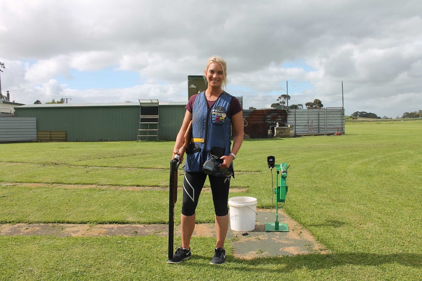 Liz Rymill, SA representative sport shooter stands with rifle at a gun range.