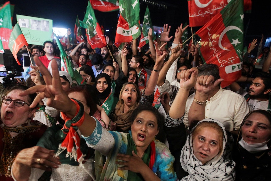 Women wave flags and gesture in support of Imran Khan`s party