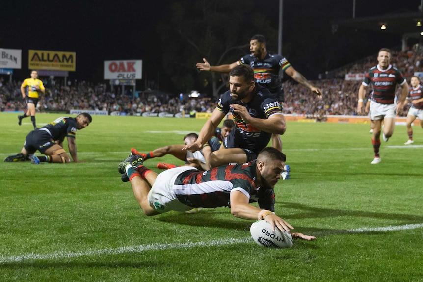 Corey Allan dives with his left arm outstretched as he is about to ground the ball for a try.