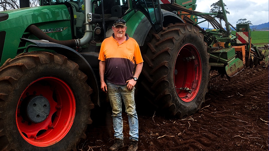 Potato farmer Mark McDougall stands in front of a tractor, 2016