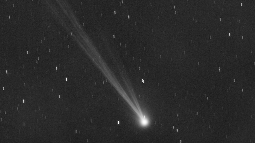 A comet flies through space, only blackness and a few stars are visible in the background. 