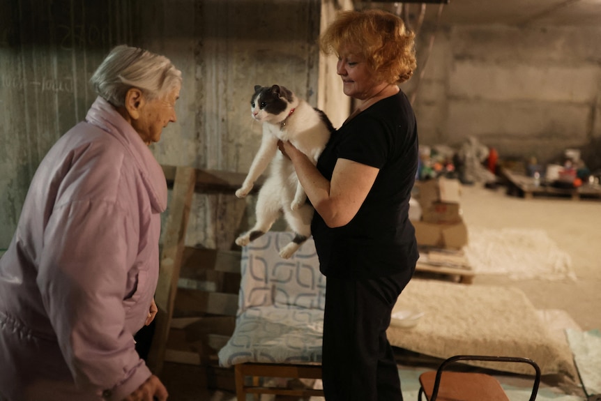 Maria Nikolaevna, 92, talks with the family cat, Kissa, who was stopped by her daughter Natalia