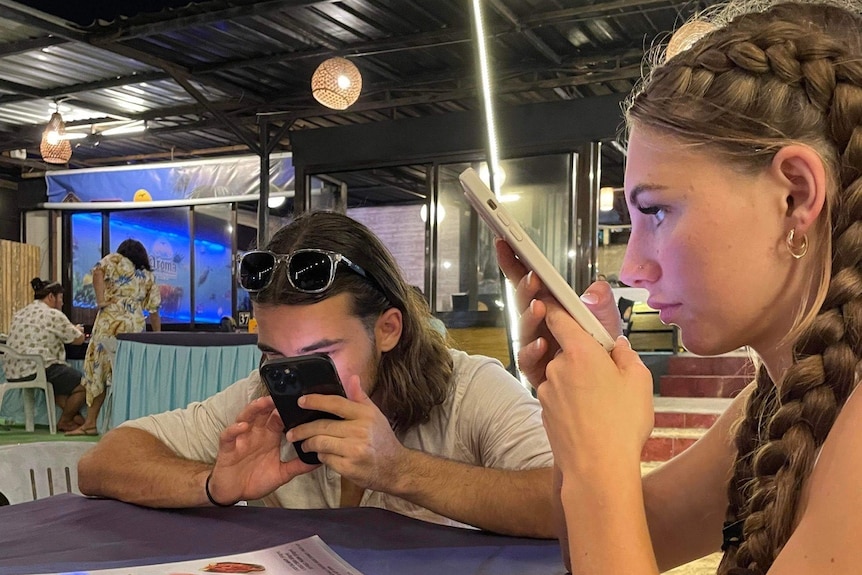 Man and woman holding phones close to their faces in cafe setting