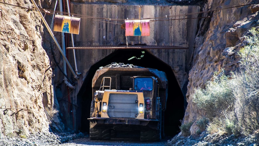 A mining truck drives out of an underground portal.