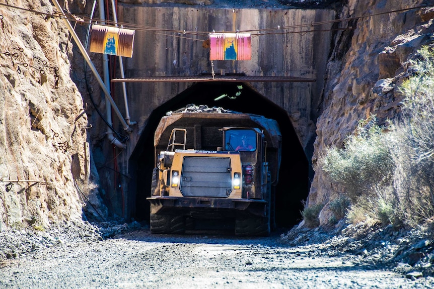 A mining truck drives out of an underground portal.