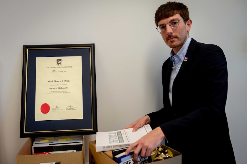 A man standing beside his doctorate