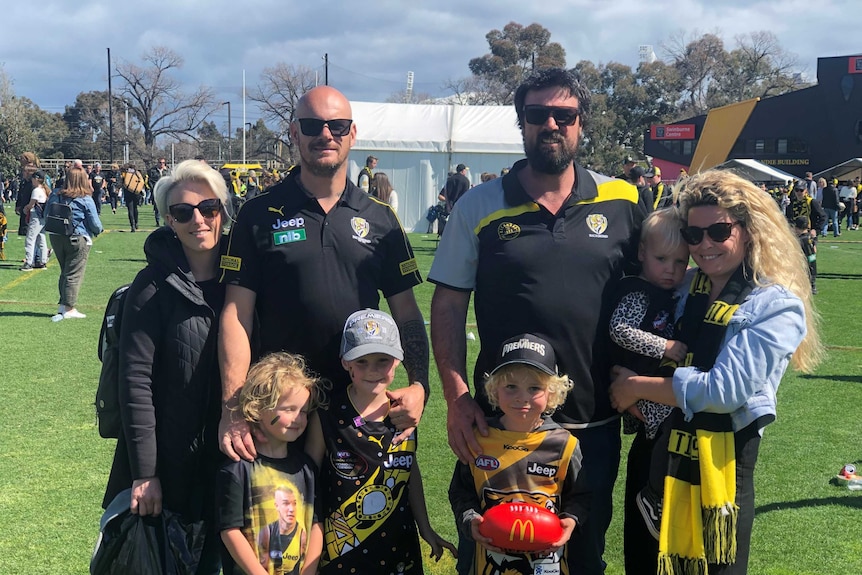 Two families with children smile, wearing Richmond gear.