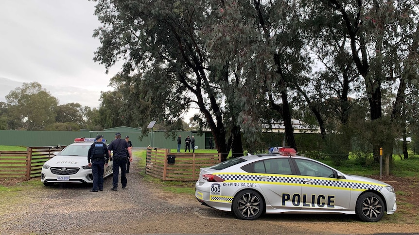 Police officers and two police vehicles outside a house