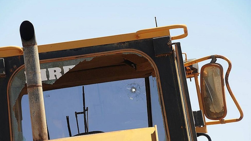 Close-up of bullet holw in windscreen of front-end loader