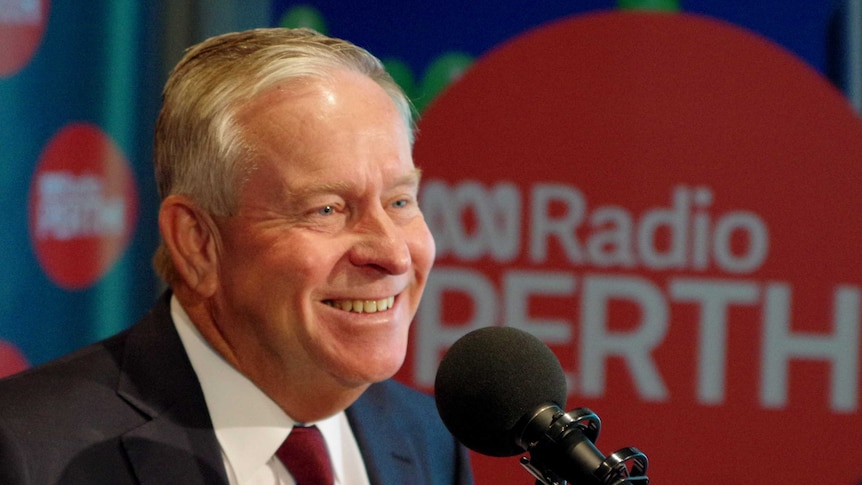 Colin Barnett smiles in front of a microphone  surrounded by ABC Radio signage.