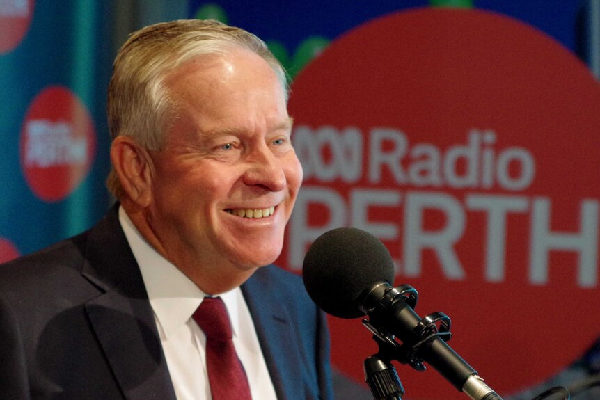 Colin Barnett smiles in front of a microphone  surrounded by ABC Radio signage.
