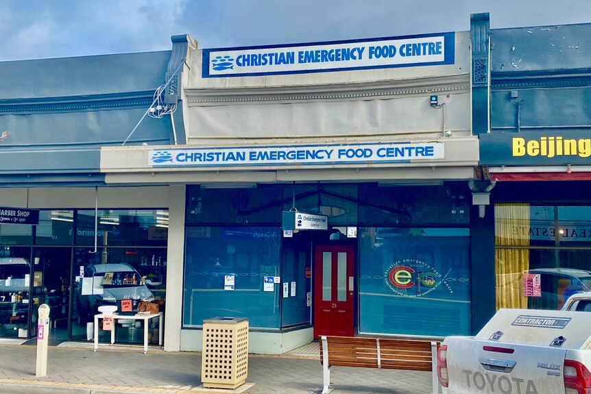 A blue and white shopfront with a sigh that reads 'CHRISTIAN EMERGENCY FOOD CENTRE'.