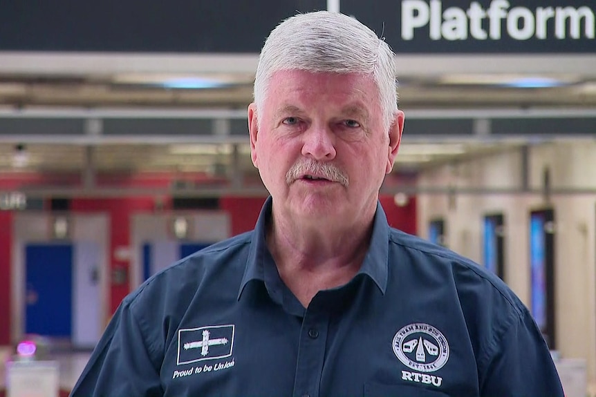 an elderly  man talking at a train station