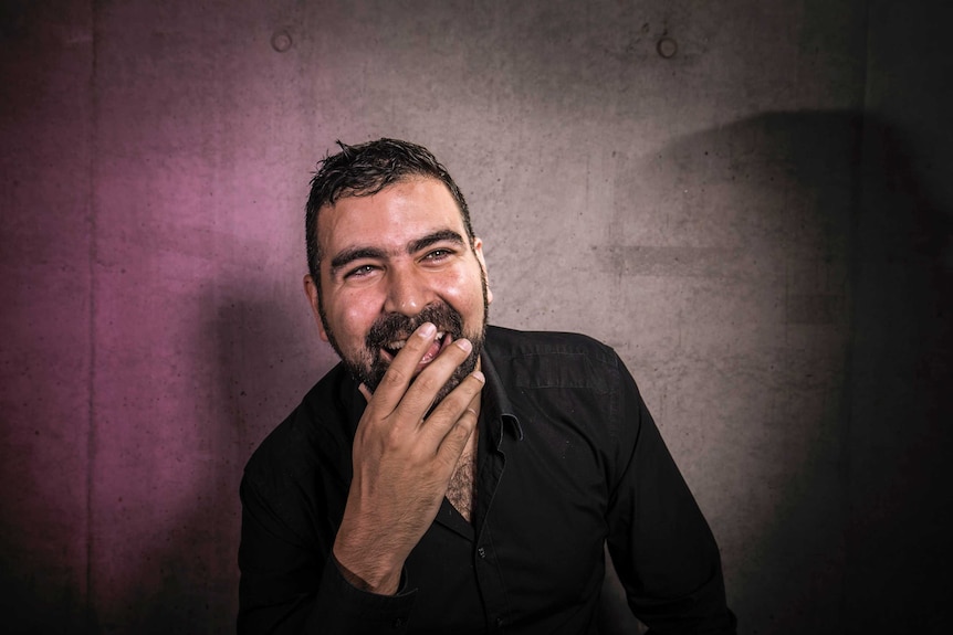 Colour photograph of Performance Space Artistic Director Jeff Khan laughing in front of a concrete wall.