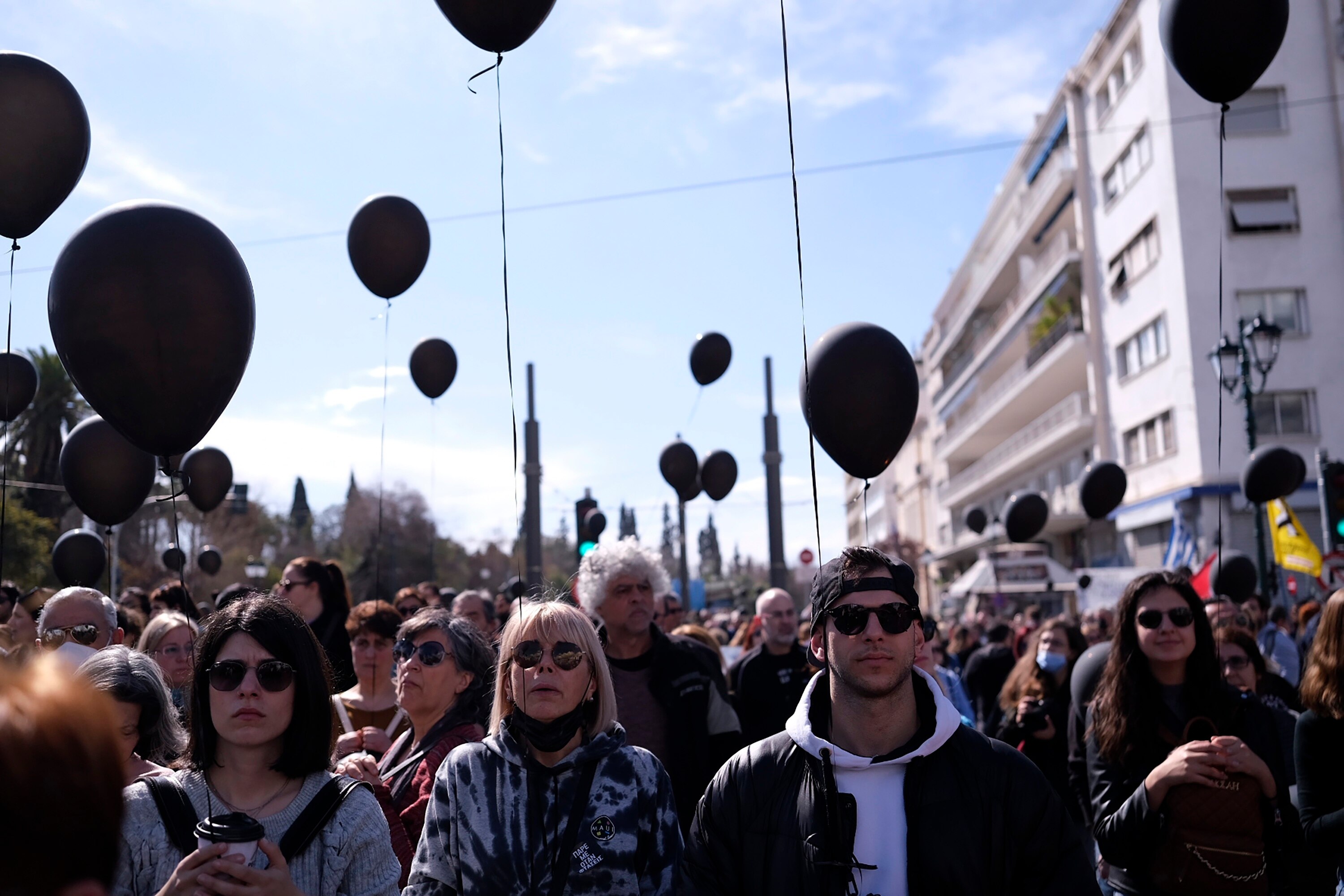 People march while holding black balloons.