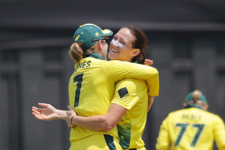 Two female cricketers embrace to celebrate a wicket in a T20 match against India in Mumbai
