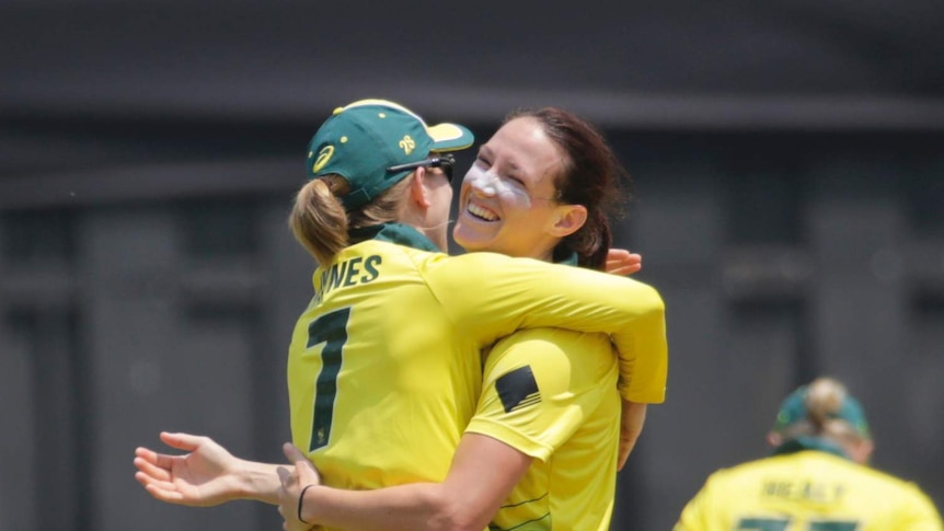 Two female cricketers embrace to celebrate a wicket in a T20 match against India in Mumbai