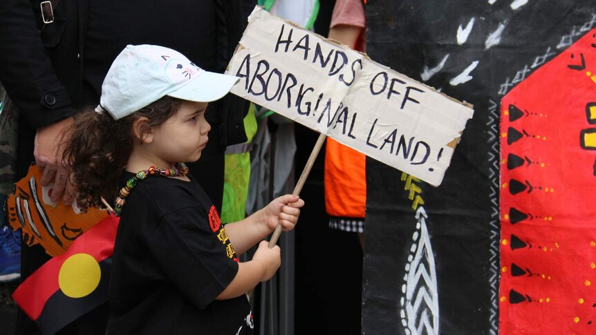 young girl holding a sign that read hands off aboriginal land