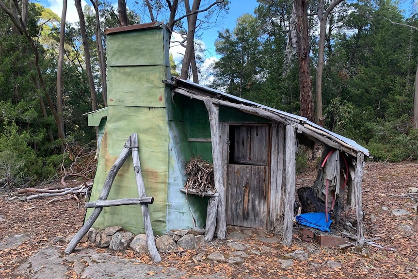 A small hut that looks like it's patched together from different materials and has a chimney and a single door