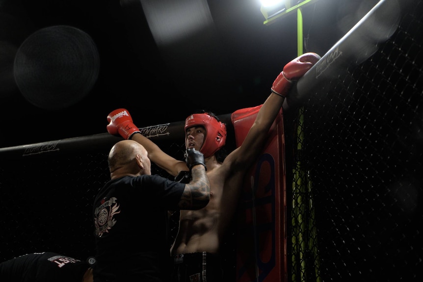 coach talking to fighter in corner, arms spread wide
