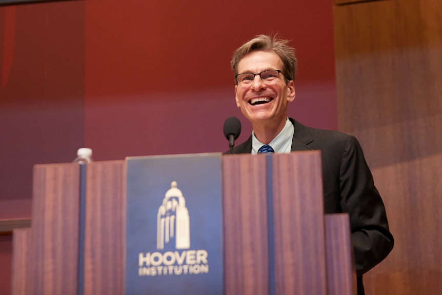 Economist John H Cochrane speaks at a podium with Hoover Institution sign.