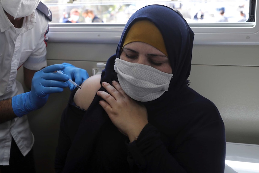 A Palestinian woman receives the Pfizer coronavirus vaccine