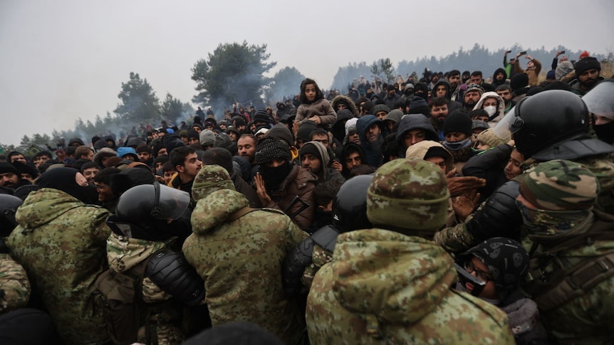 A large crowd of migrants at the Polish-Belarusian border are held back by a line of soldiers