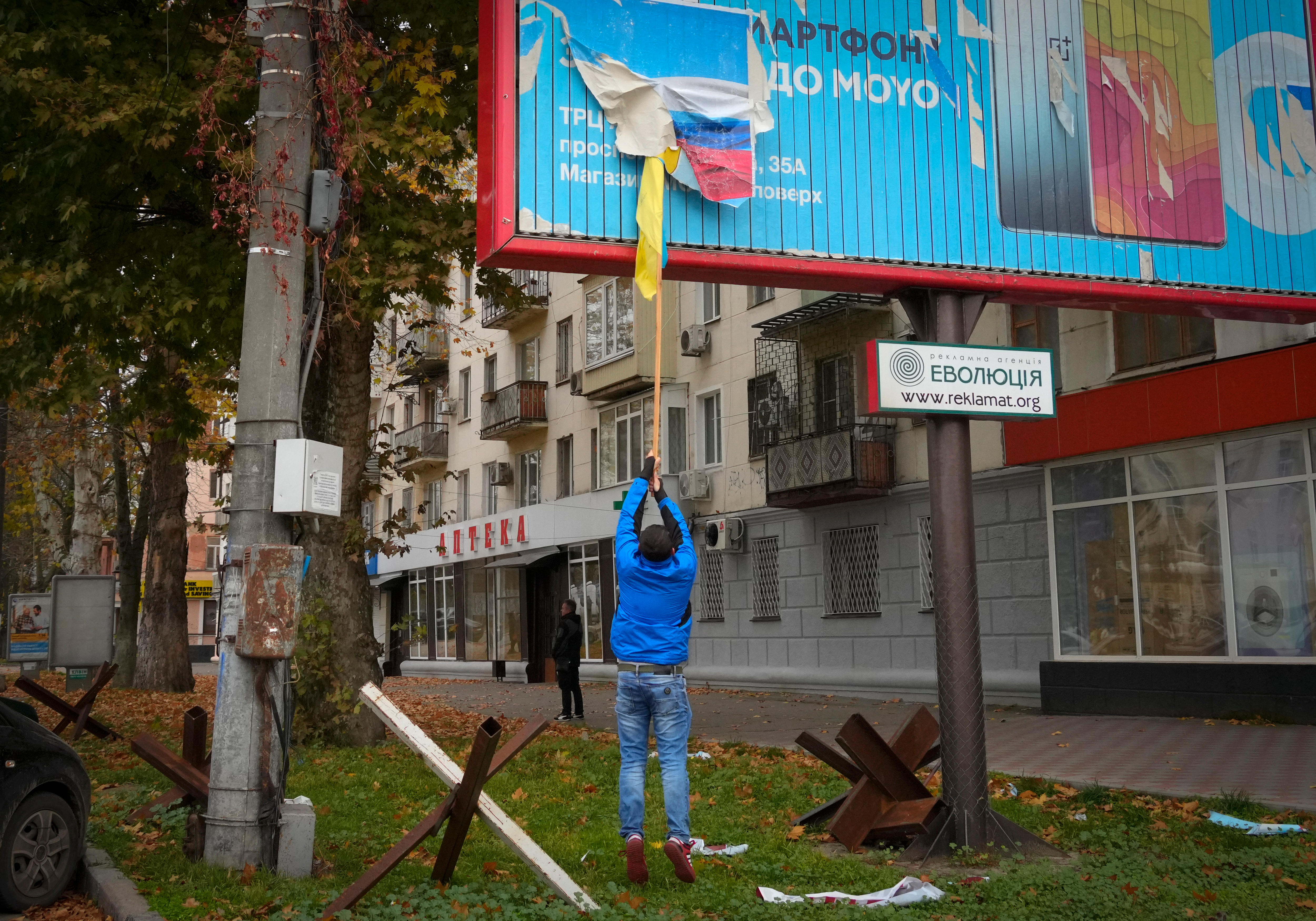 A man reaching up a billboard scrapping off a sign