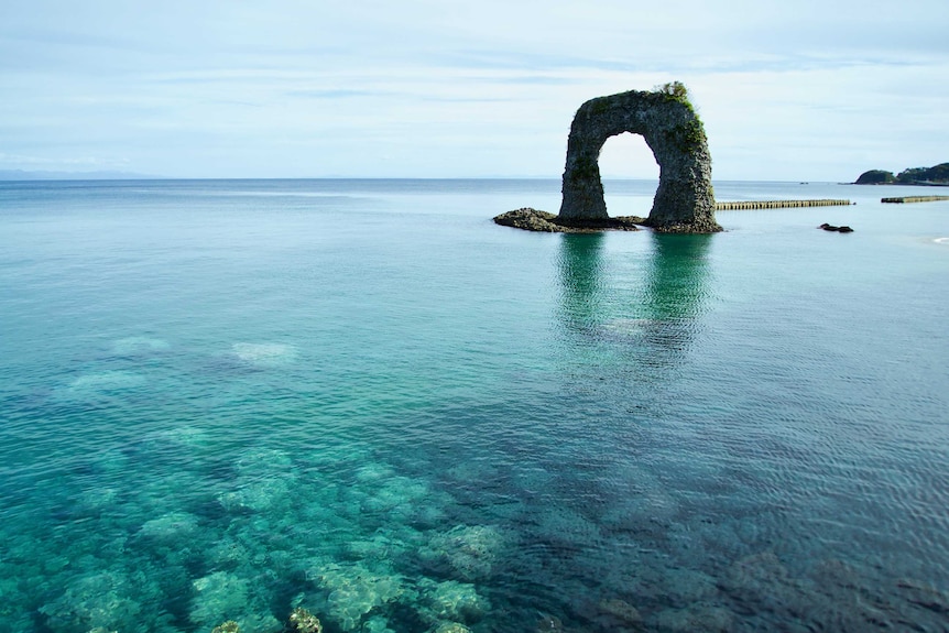 A photograph over an ocean, showing circular rock formation