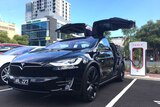A Tesla car plugged into a charging station