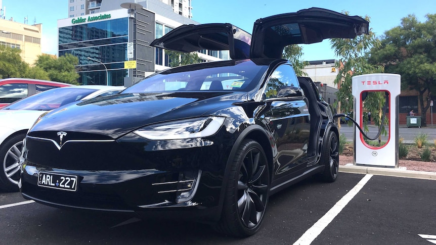 A Tesla car plugged into a charging station