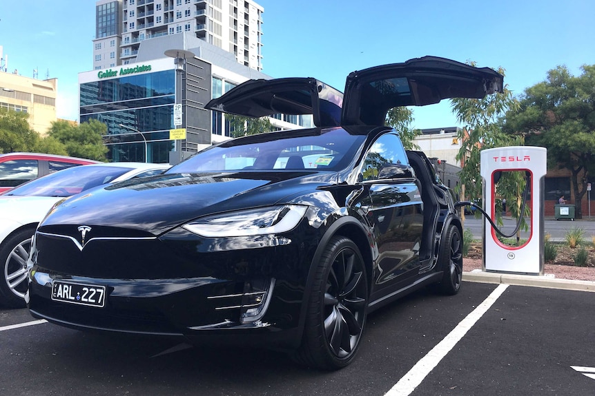 A Tesla car plugged into a charging station