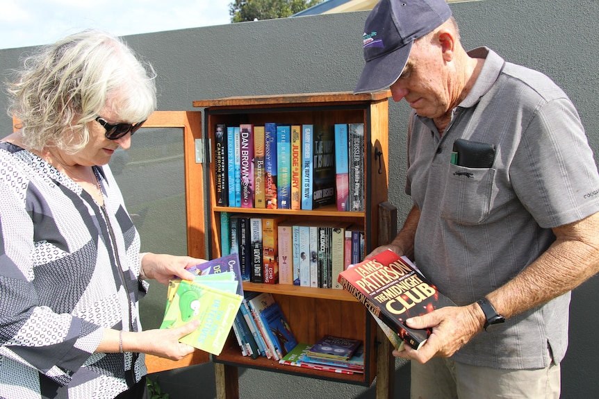 A man and a woman look down at the books they hold in their hands