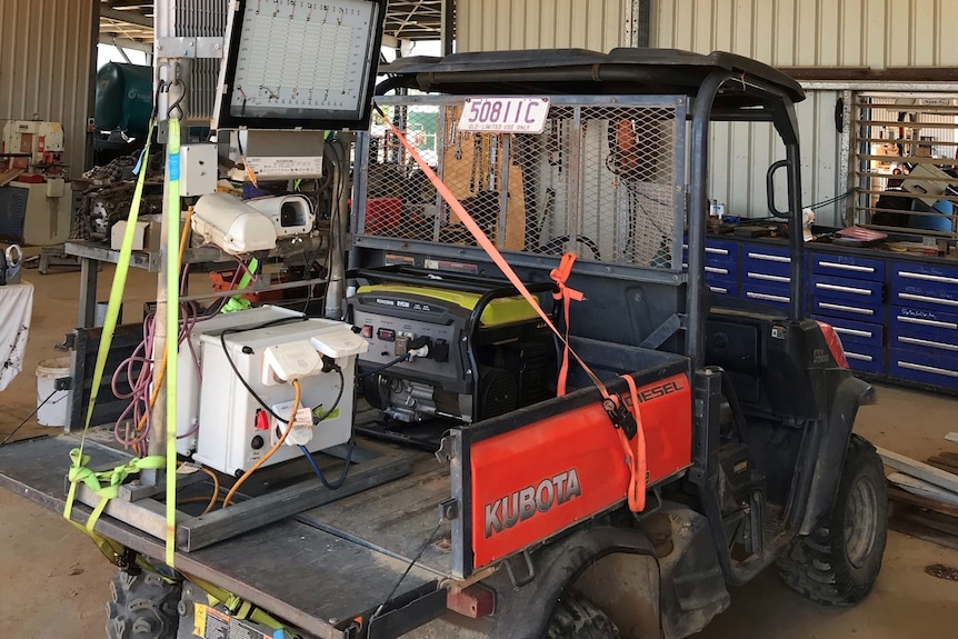 A small four-wheel buggy in a farm shed with computer equipment strapped into the tray at the back.
