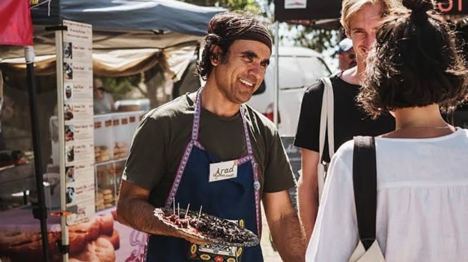 Man standing with a plate of food talking to passersby.