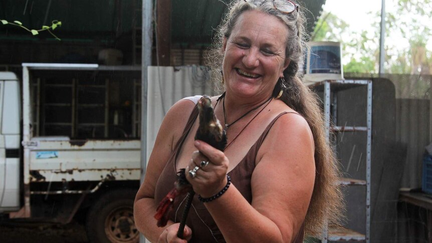 A photo of Nicola Collins attaching a magpie goose's head to a stick she will use to feed her croc.