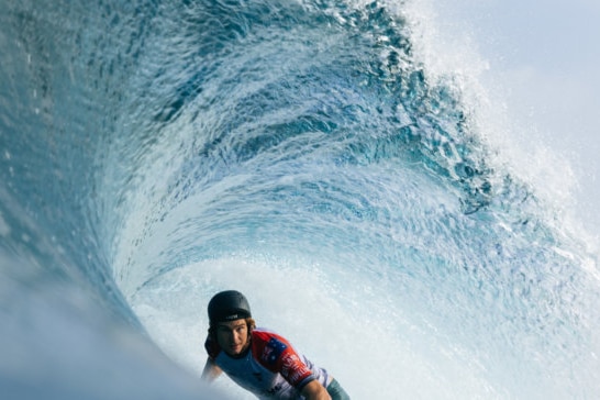 a pro surfer riding a barrel with a helmet on